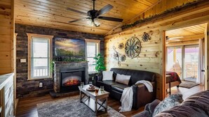 Ein gemütliches Wohnzimmer mit Kamin, einer Couch und einem Deckenventilator.