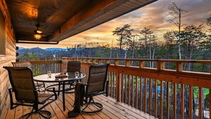 Eine Holzdielen-Terrasse mit Tisch und Stühlen mit Blick auf eine bewaldete Landschaft.