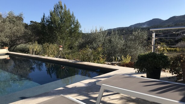 Ein Poolbereich mit Liegestühlen und Blick auf eine Berglandschaft.