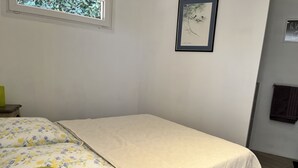 Ein Schlafzimmer mit Bett, Fenster, einem gerahmten Bild an der Wand und einem Handtuchhalter.