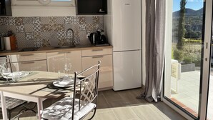 Eine moderne Küche mit einem Kühlschrank von Bosch, einer gestreiften Spritzschutzleiste und einem Essbereich mit Tisch für zwei Personen.