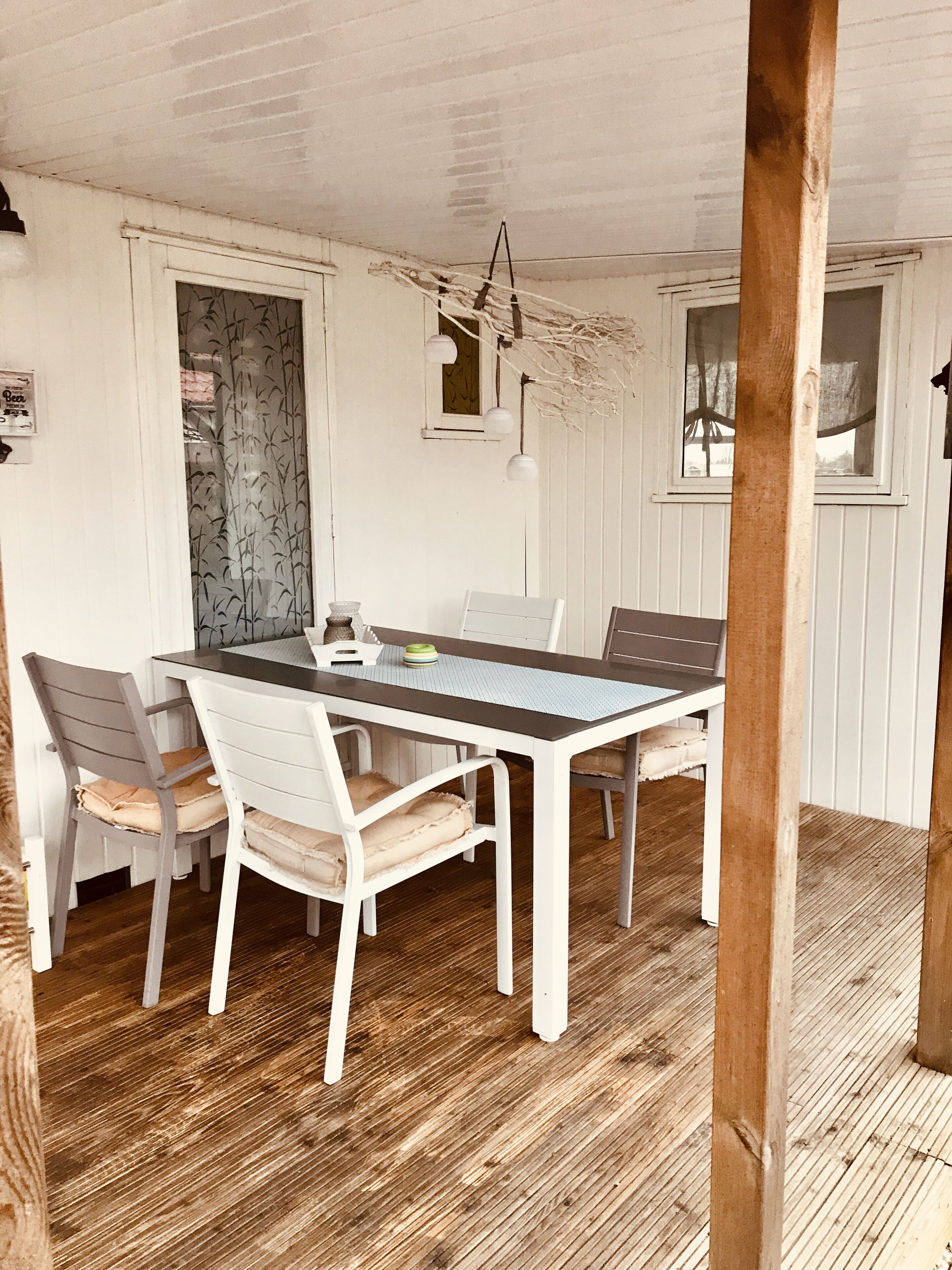 A dining area with a wooden table and chairs, white walls, and a wooden floor.