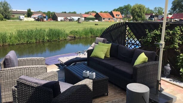 Une terrasse extérieure aménagée avec des meubles en osier, une table et un parasol.