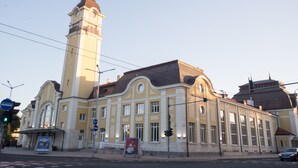 Um edifício histórico com uma torre do relógio imponente e uma grande janela central.