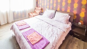 Quarto com cama, almofadas, uma cadeira, ar condicionado e parede estampada.