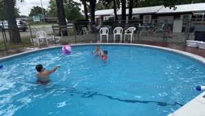 Ein Schwimmbecken mit einer Seillane, umgeben von weißen Stühlen und einem Zaun.
