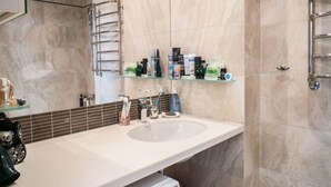 A bathroom with a large sink, a glass shelf with toiletries, and a towel rack. - Apartment (Minsk)