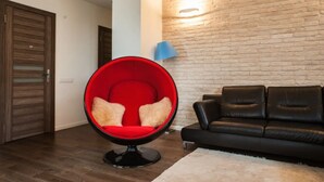 A modern living room with a red egg chair, black leather sofa, and a brick wall. - Apartment (Minsk)