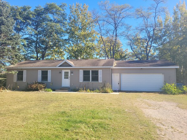 A single-story house with a garage, a front door, and a small front yard.