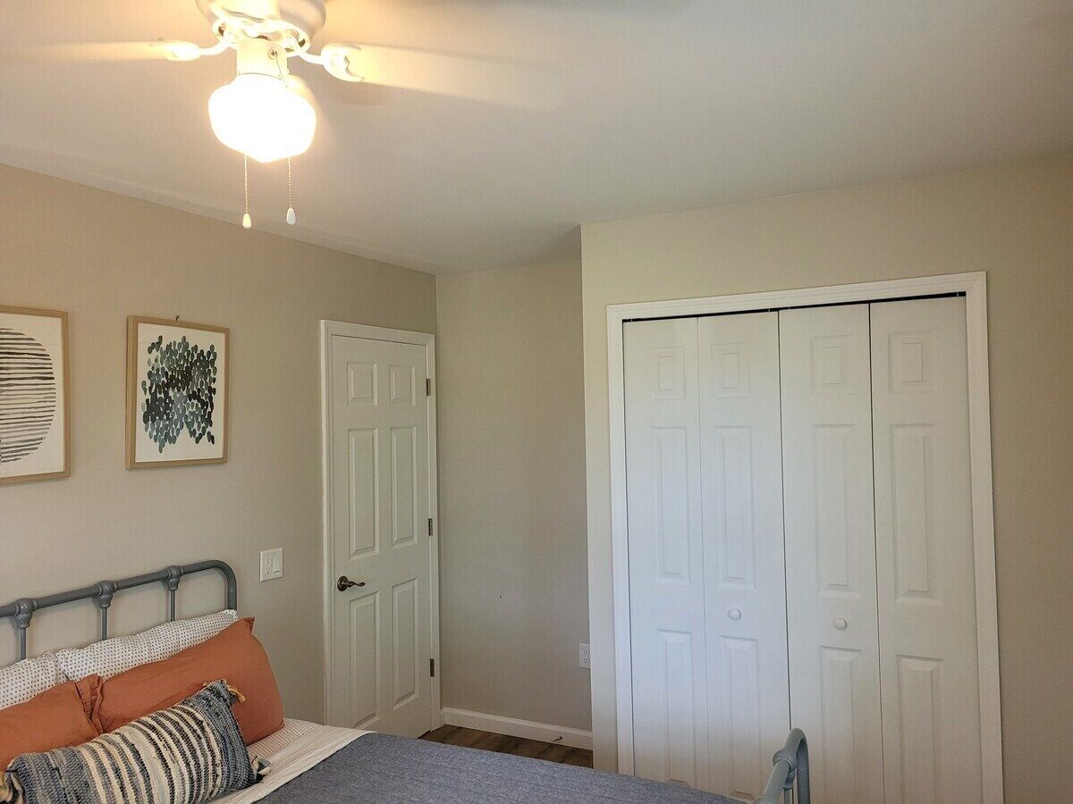 Un dormitorio con una cama, un ventilador de techo y dos puertas blancas.