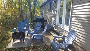 A patio with Adirondack chairs, a grill, and a black pot. - White Birch - Riverfront and Newly-Remodeled!  Great Location! (Elberta)