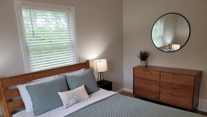 A bedroom with a bed, a dresser, a mirror, and a window with blinds. - White Birch - Riverfront and Newly-Remodeled!  Great Location! (Elberta)