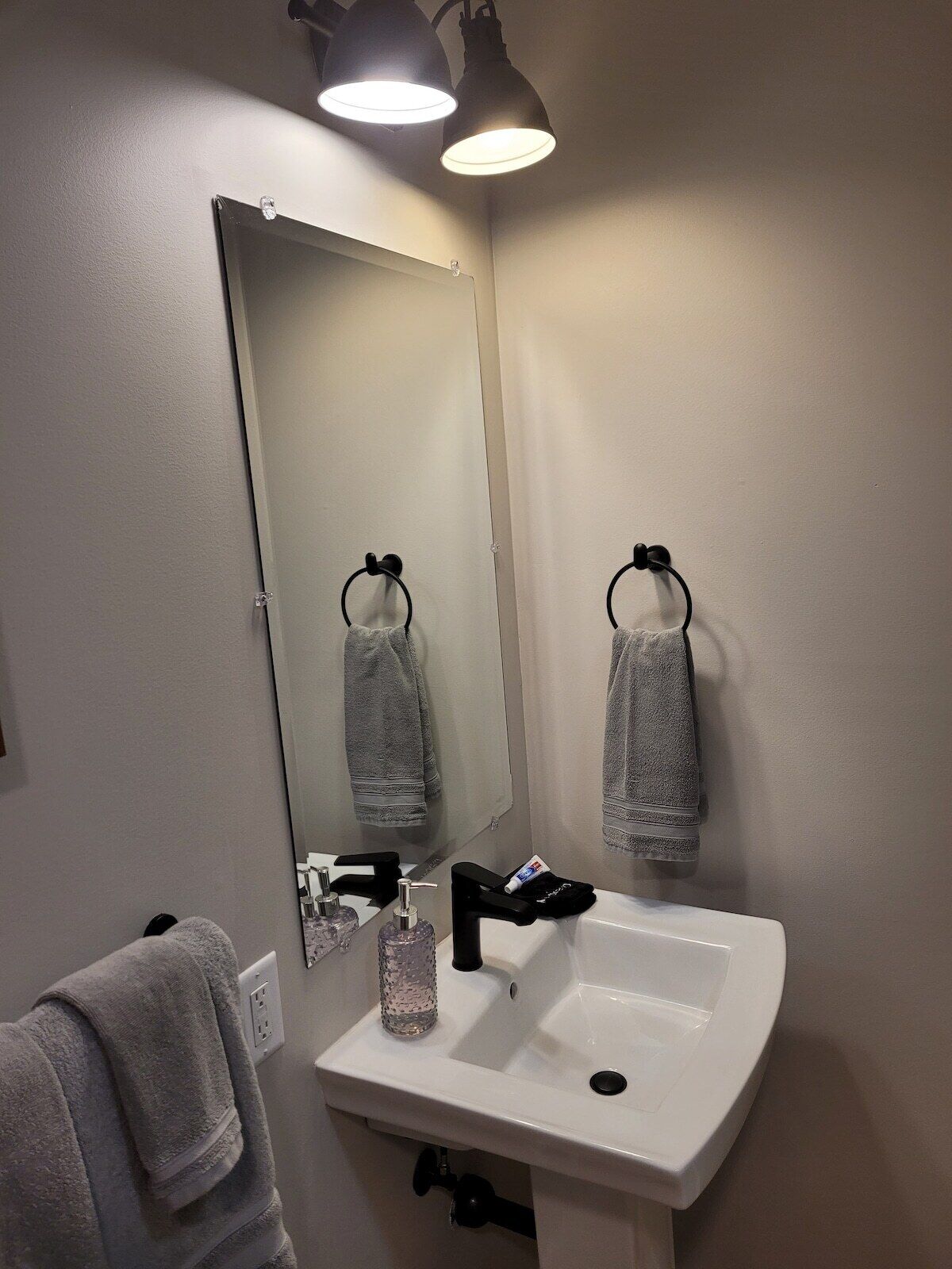 A bathroom with a white sink, a mirror, and two towels hanging on towel rings.