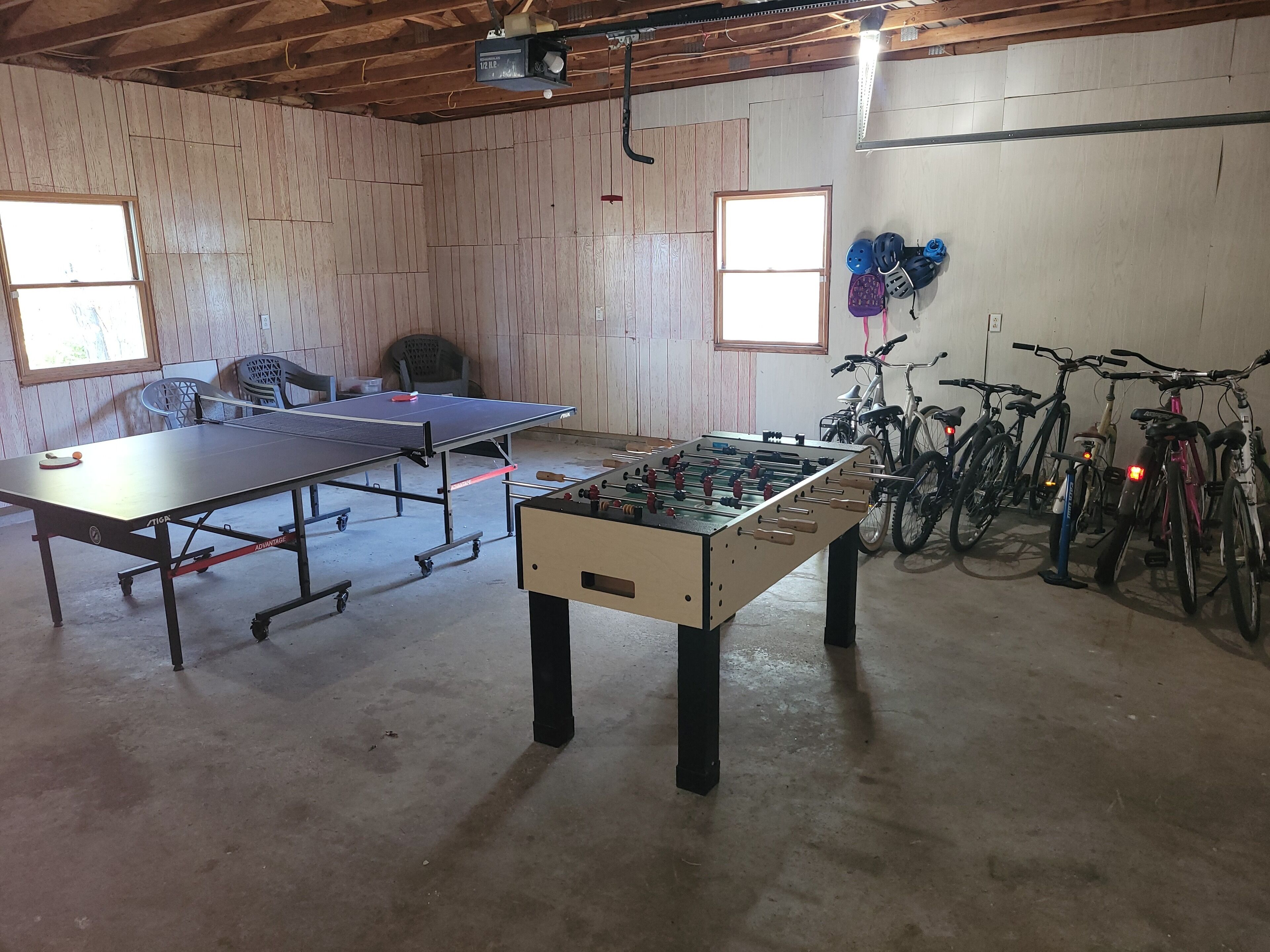 Une pièce équipée d’une table de ping-pong, d’un baby-foot et de vélos.