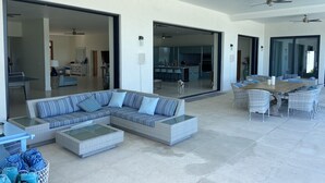 Un'ampia zona living con un grande divano componibile, un tavolo da pranzo con sedie e una cucina sullo sfondo.