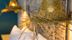 A woven straw hat with a light pattern, displayed against a textured wall. - Numero Uno Piñones Short Term Rental (Loiza)