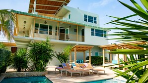 A two-story house with a pool, outdoor seating, and a covered patio area. - Numero Uno Piñones Short Term Rental (Loiza)