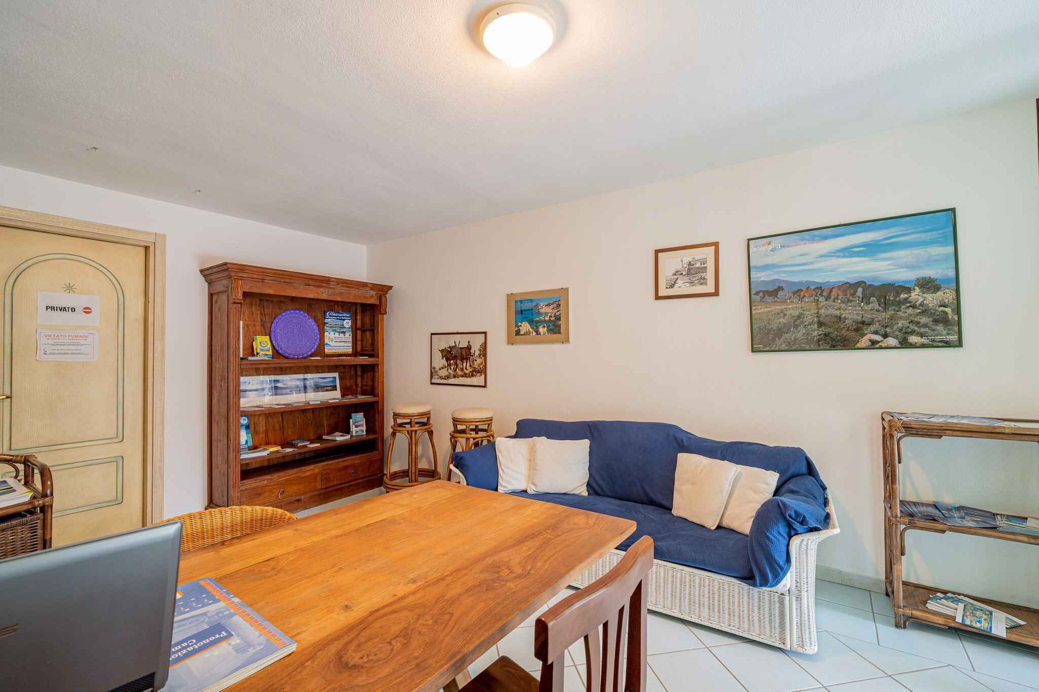 A cozy living room with a wooden dining table, a blue sofa, and a bookshelf.