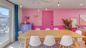 A bright room with a pink wall, a wooden table, white chairs, and a ceiling with colorful hanging lights. - Spacious 5-Bedroom Retreat - Hot Tub - Games (Denver)