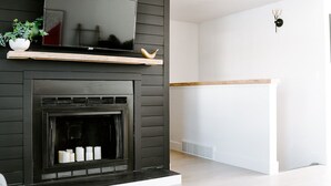 A modern living room with a fireplace, a mounted TV, and a minimalist design. - Spacious 5-Bedroom Retreat - Hot Tub - Games (Denver)
