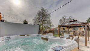 A hot tub with a control panel, surrounded by outdoor furniture and a pergola. - Spacious 5-Bedroom Retreat - Hot Tub - Games (Denver)