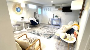 Un salon moderne comprenant un canapé, des fauteuils, une table basse et un coin repas avec une table et des chaises.