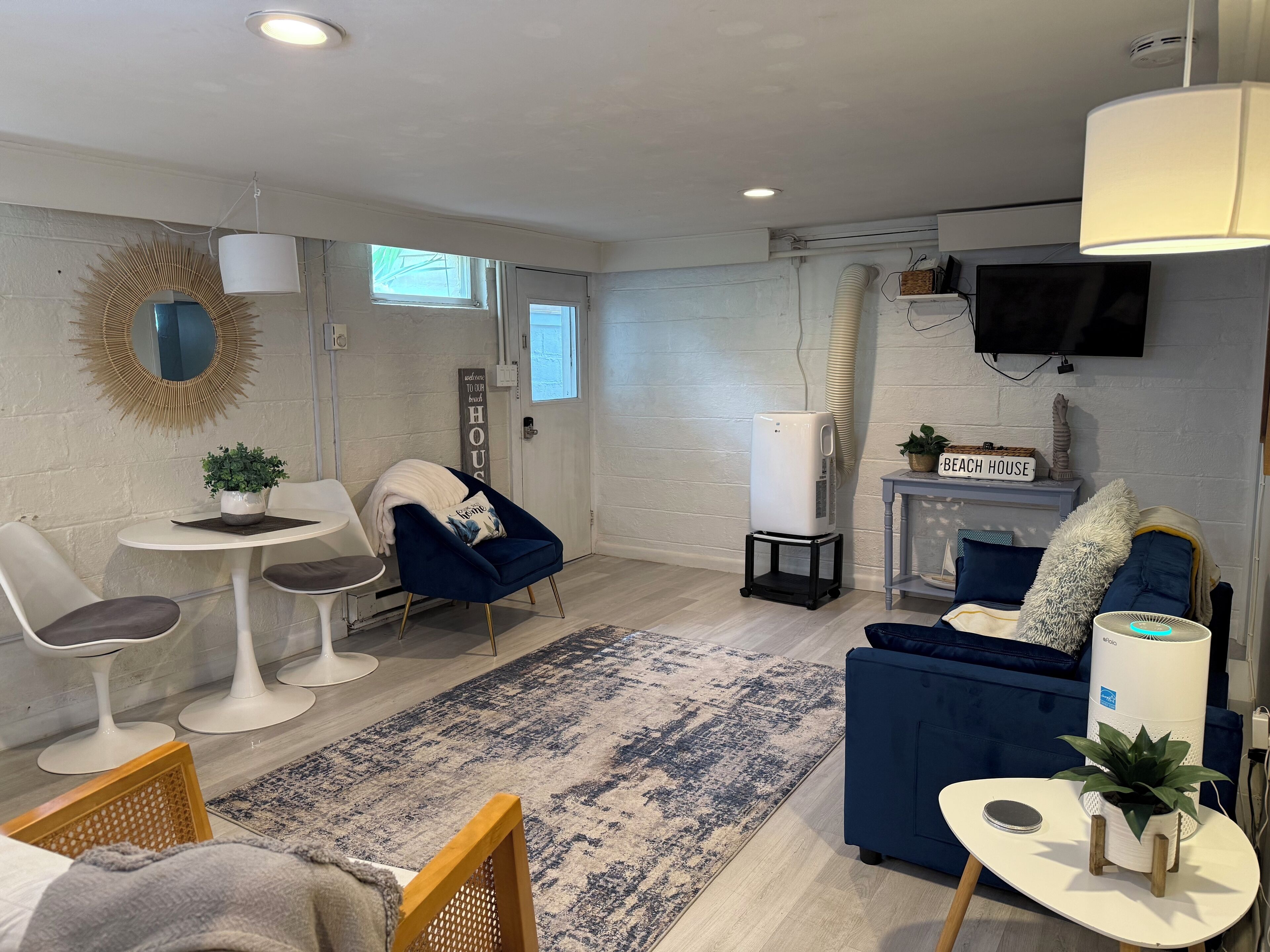 Una sala de estar moderna con un sofá blanco, un sillón azul, una mesita con una planta y un sofá azul.