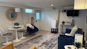 Una sala de estar moderna con un sofá blanco, un sillón azul, una mesita con una planta y un sofá azul.