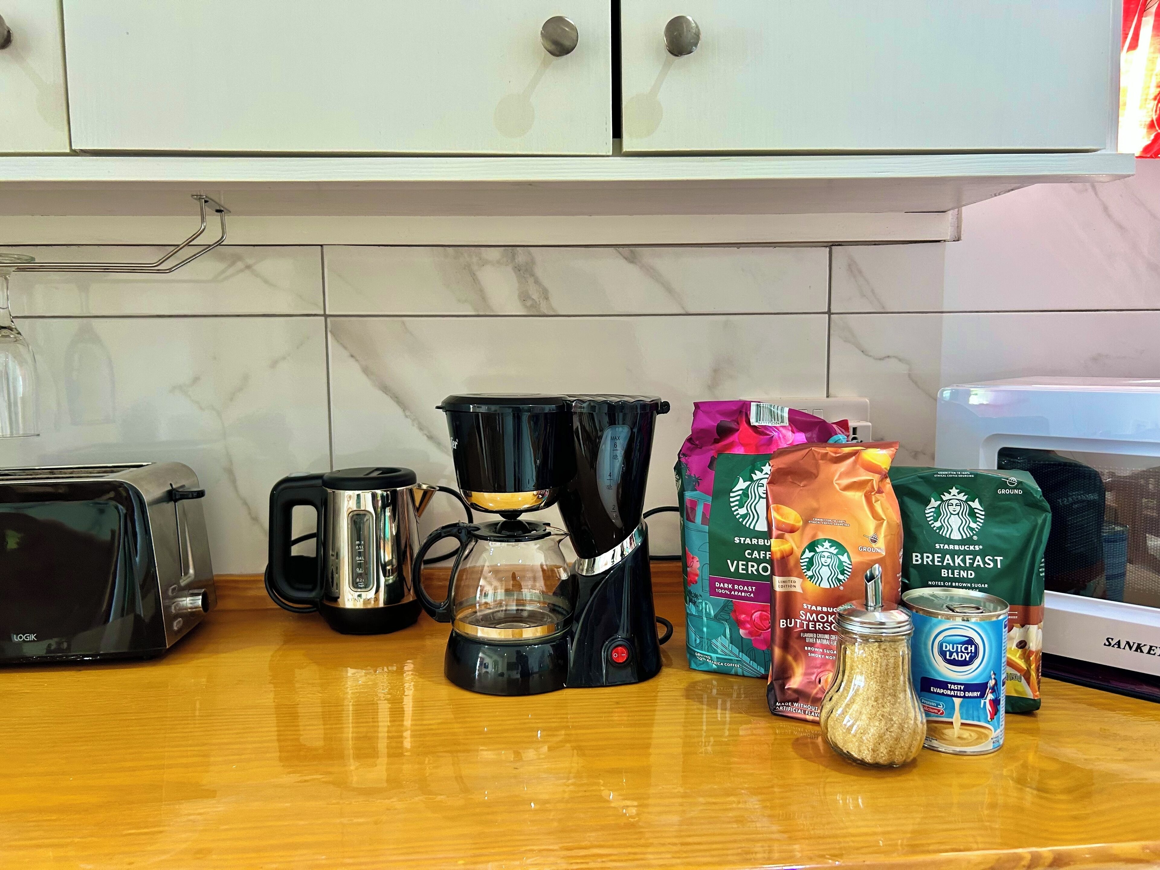 A kitchen counter with a toaster, coffee maker, and various coffee bags.