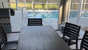 A covered outdoor area with a pool, a table, and chairs. - Serene, Spacious 3 Bedroom Pool Home 7 min from WEC! (Ocala)
