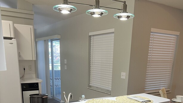 A modern kitchen with a central island, dark wooden chairs, and a dining area with a table and chairs. - Serene, Spacious 3 Bedroom Pool Home 7 min from WEC! (Ocala)