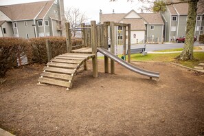 Une aire de jeux avec un toboggan en bois et des structures d’escalade.