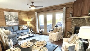 Un salon chaleureux avec une cheminée, un canapé, une table basse et un coin repas agrémenté de sets de table et de serviettes.
