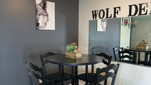 Un comedor con una mesa redonda y seis sillas, una lámpara de pared y dos imágenes enmarcadas de lobos.