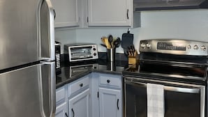 Una cocina con electrodomésticos de acero inoxidable, armarios azul claro y piso de madera.