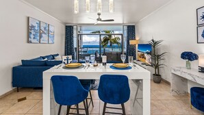 Cocina moderna con una isla central, sillas azules y una mesa de comedor para cuatro.