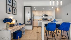 Una cocina moderna con encimera de mármol, zona de comedor con sillas azules y una isla de cocina.