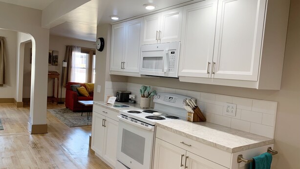 A modern kitchen with white cabinets, a built-in microwave, a stove, and a sink. - 2-Bedroom Luxury Loft in the Heart of Downtown Munising (Munising)