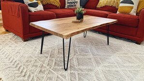 A red sofa with multiple cushions, a wooden coffee table, and a white textured rug. - 2-Bedroom Luxury Loft in the Heart of Downtown Munising (Munising)