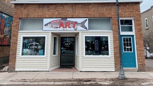 A two-story building with a sign for 'Kelley X Marketing' at the top. - 2-Bedroom Luxury Loft in the Heart of Downtown Munising (Munising)