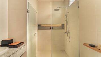 A modern bathroom with a glass-enclosed shower, a built-in shelf, and a wooden bench.