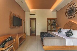 A hotel room with a bed, a TV, a wooden bench, and a decorative wall piece. - Aeera Villa Canggu by Ini Vie Hospitality (Canggu)