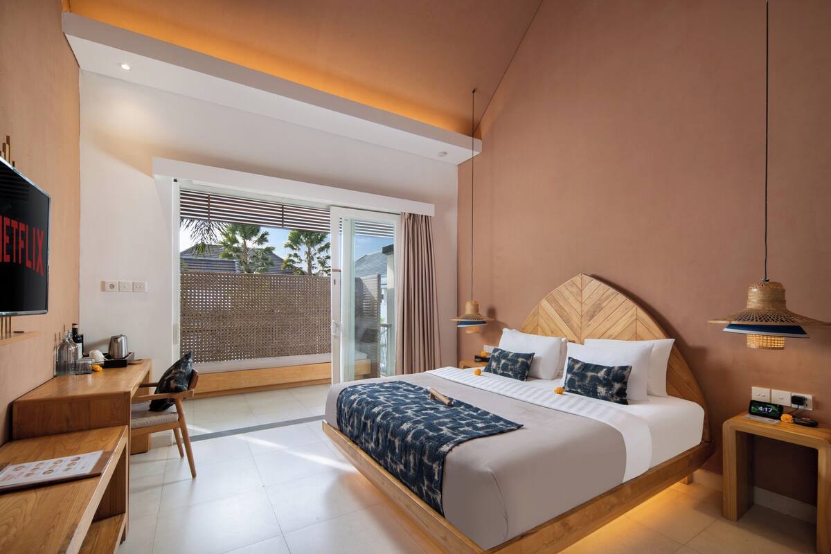 Habitación de hotel moderna con una cama grande, un escritorio, televisión y vistas al exterior.