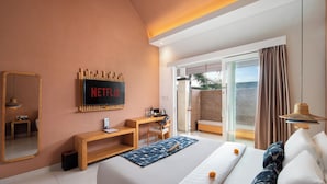 Una habitación de hotel moderna con una cama grande, un escritorio, un televisor y un ventanal corredero al exterior.