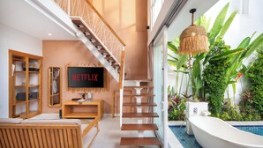 Un interior moderno con escalera, televisor de pantalla plana, piscina y plantas de interior.