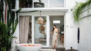 Una casa moderna con una piscina grande al aire libre, un ventanal corredero y una mujer con vestido.