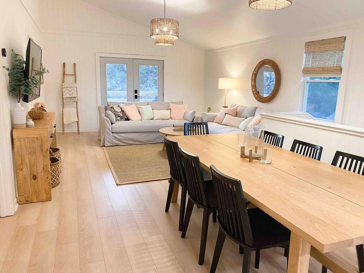 Una sala de estar moderna con una gran mesa de comedor de madera, un sofá y una zona de cocina.