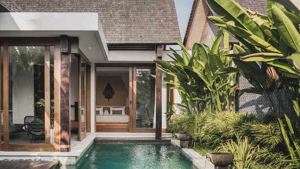 Uma casa moderna com piscina, janelas amplas e plantas tropicais.