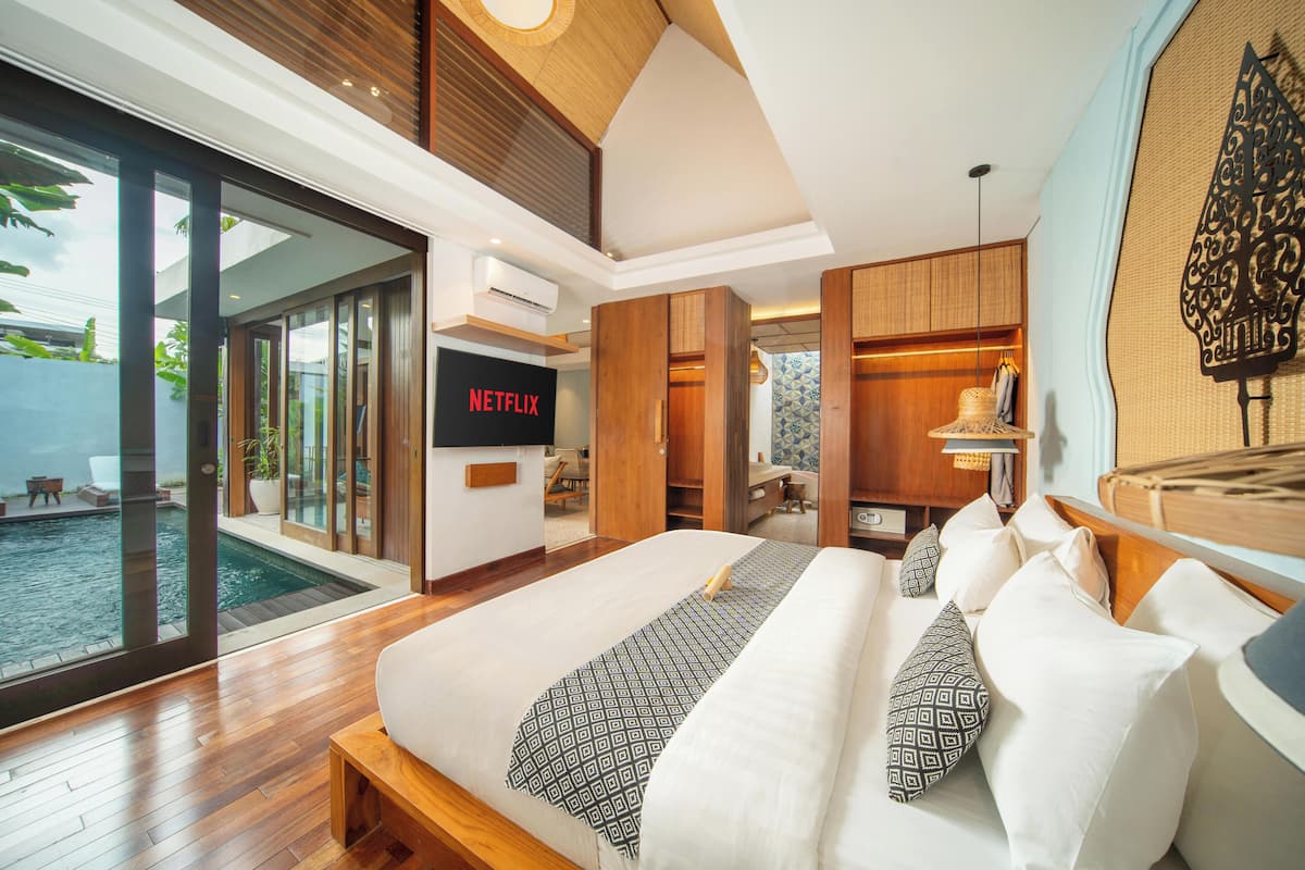 Une chambre moderne avec un grand lit, une télévision et une vue sur une piscine.