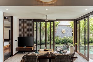 Un interior moderno con comedor, televisor y vistas al exterior.